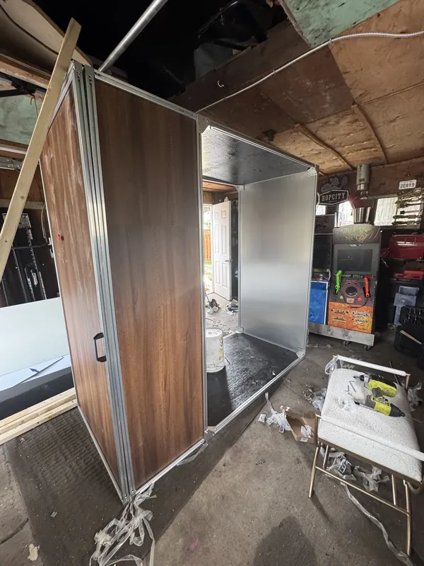 Bare aluminum frame and wood-grain panel in a garage