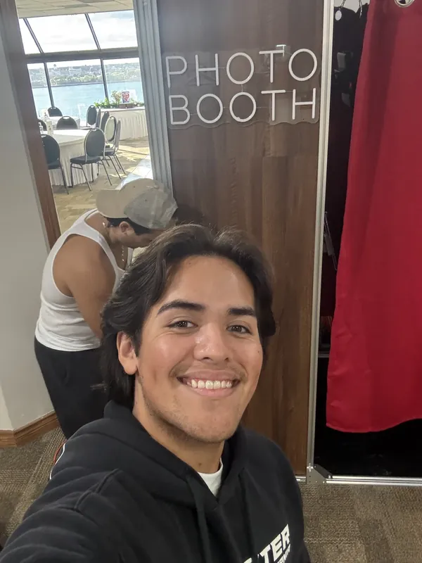 Nathan and a friend taking a selfie beside the finished booth at the venue