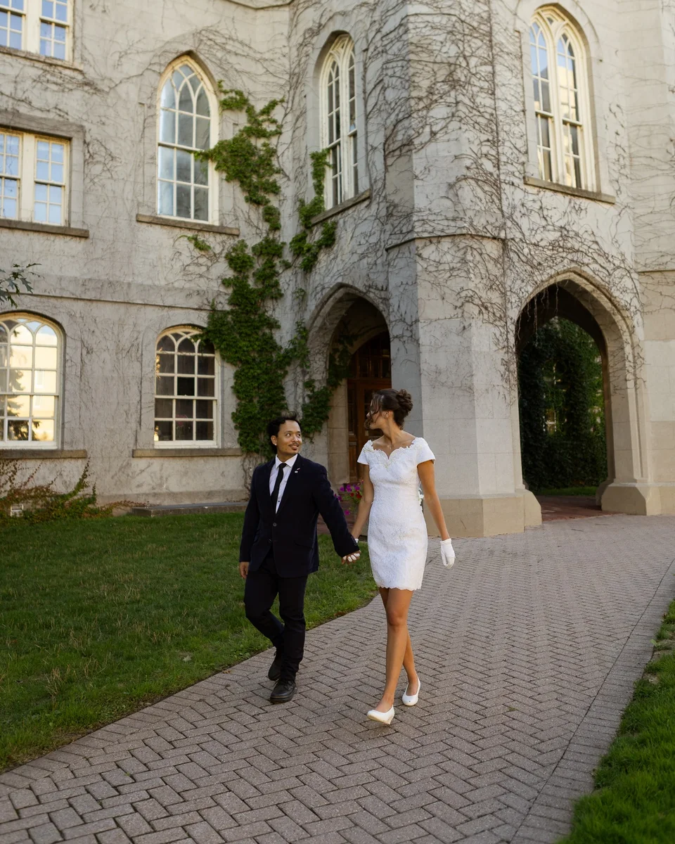 Nathan and Morgan walking hand in hand in front of an ivy-covered stone building