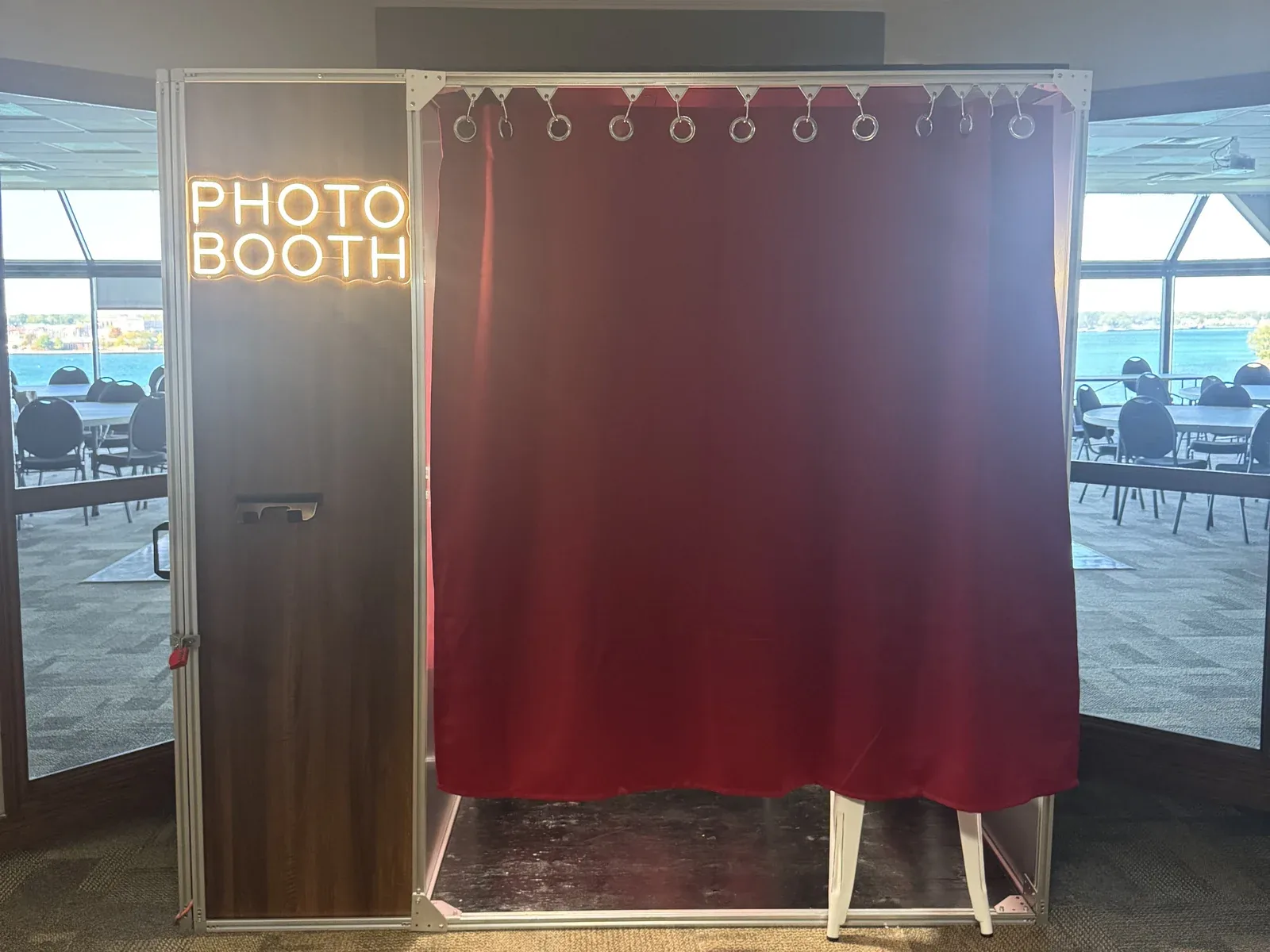 The real booth set up in a waterfront event room, neon sign lit and red curtain closed